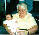 Granma & baby granddaughter sitting in upholstered chair.