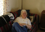 Carole resting on a couch, propped up with pillows. Visiting at a friend's house.