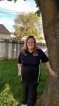 Esther Collingwood standing by a tree in a backyard.