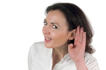 A woman holding her hand to her ear, listening.