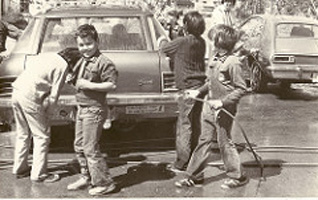 Black and white picture of a group of boys washing car.