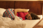 Woman curled up in bed, in pain