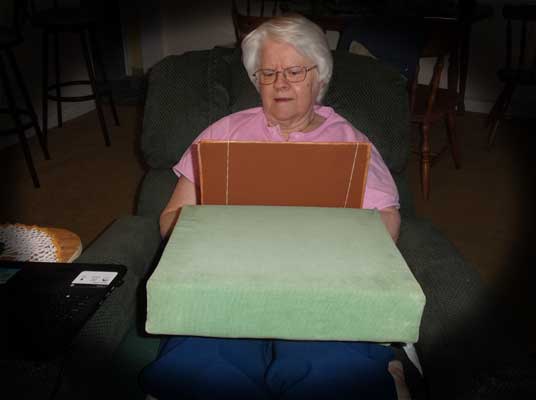 Carole using 2 pillows and board to read