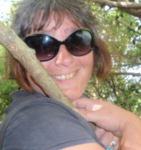 Trish Veltman, smiling, standing in front of trees.