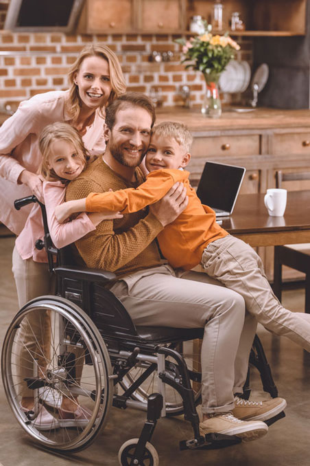 Dad in wheelchair, mother, son, daughter all hugging.