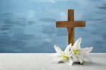 Wooden cross and white lily on table