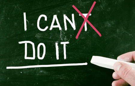 Hand holding chalk after writing on greenboard: " I CANT do it" with "T" crossed out in red.