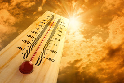 Very hot thermometer, over 100, in front of bright, shining sun. Golden sky.