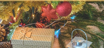Gold-wrapped gift under beautiful, colorful Christmas tree.