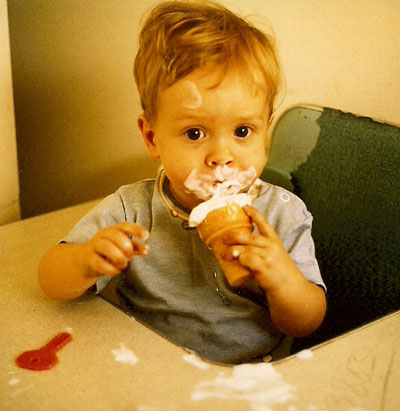 Tom with his first ice cream cone. Sitting in his eating table. Face, shirt, and table smeared.